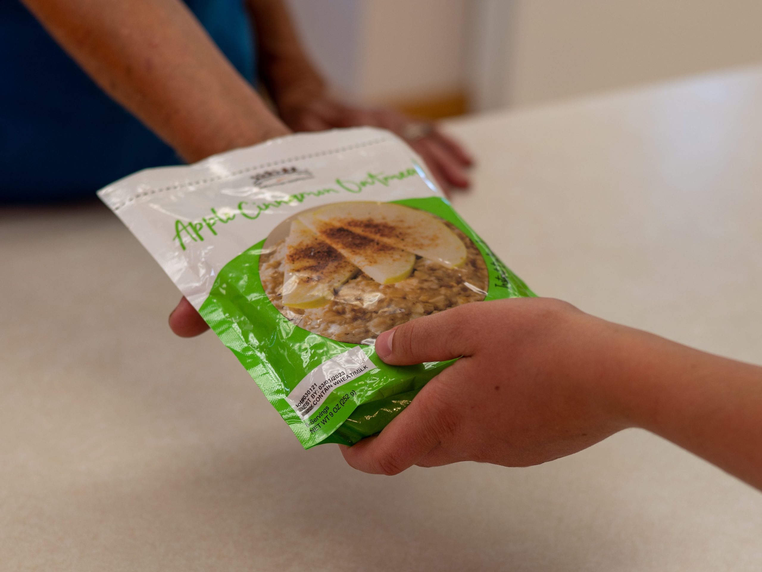 Apple Cinnamon Oatmeal package being passed across a counter top.